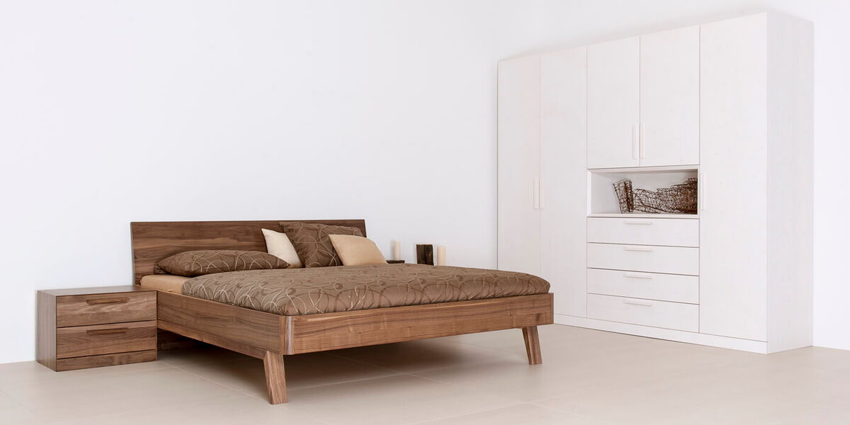 Bett CORTINA CO31 mit Holzoptik und weißem Schrank in einem modernen Schlafzimmer